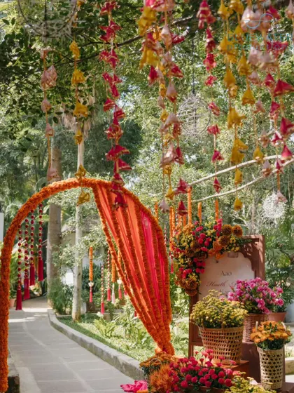 The entrance to the Haldi ceremony, with a marigold arch and hanging floral decorations.