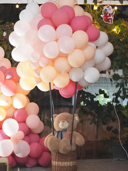 A cute prop featuring a teddy bear in a hot air balloon basket made of cane.