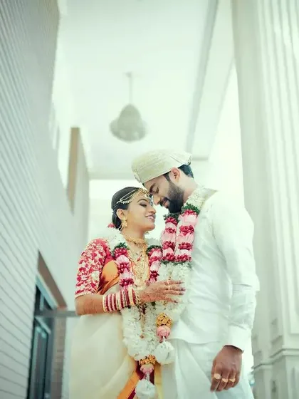 A classic, romantic portrait of a couple in their wedding attire, framed by the grand white pillars of their venue.