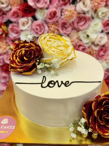 A simple and elegant cake with the word "love" piped on it, adorned with beautiful red and yellow roses. Sometimes, less is more.