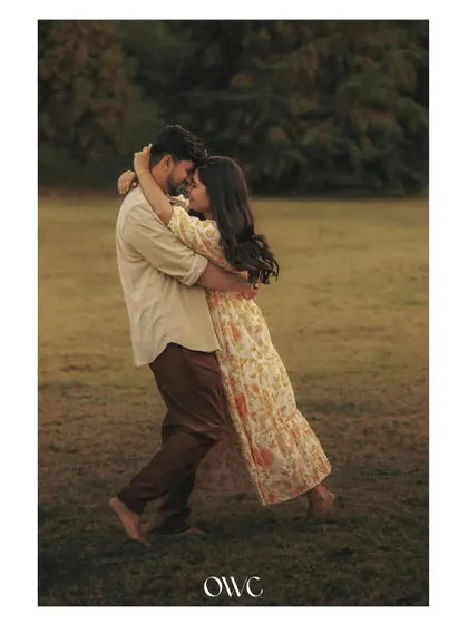 A full-length shot of a couple embracing and dancing in a field at dusk, capturing a moment of pure romance.