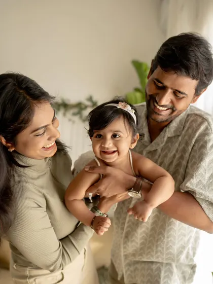 A family of three shares a laugh. The father holds their daughter, and their collective joy is beautifully captured in this candid moment.