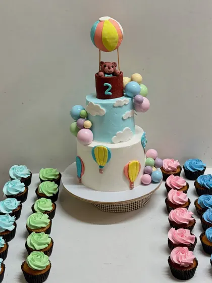 The hot air balloon cake paired with matching pastel-coloured cupcakes, creating a beautiful and cohesive dessert table.