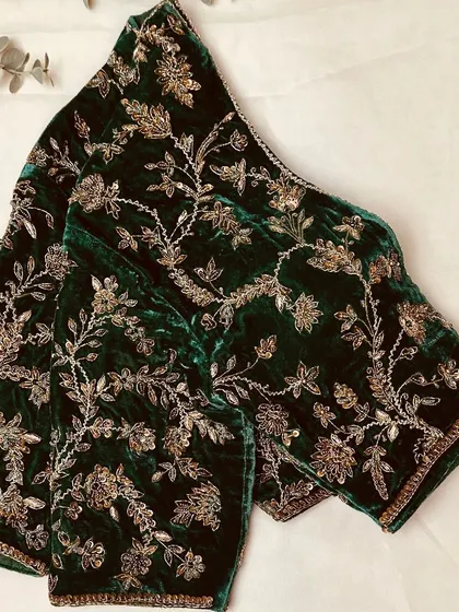 A bottle green velvet blouse adorned with detailed aari work using zardosi in a beautiful floral pattern.