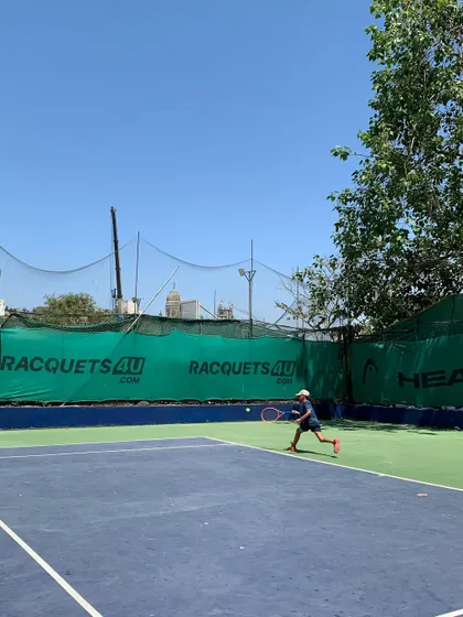 A young player in action during the TenniStation Season 12 tournament, showing focus and form during a forehand shot.