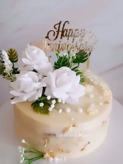 A beautiful anniversary cake in white and gold. This no-fondant design is decorated with white flowers and touches of gold leaf for a simple yet sophisticated look.