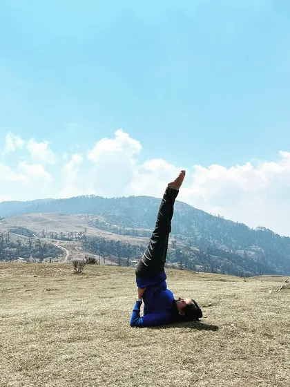 Practicing Sarvangasana, or shoulder stand, in the open meadows of the Himalayas. This inversion is calming for the nervous system and offers a new perspective on the stunning landscape.