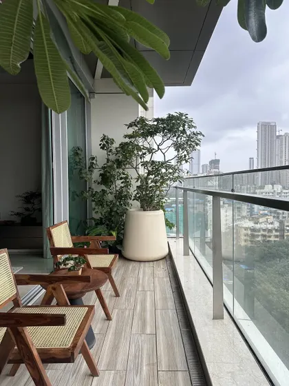 Another perspective of the balcony, showing how the wood-look floor tiles and large planters create a garden-like feel. We designed this space to be a true extension of the living area, offering a peaceful escape.