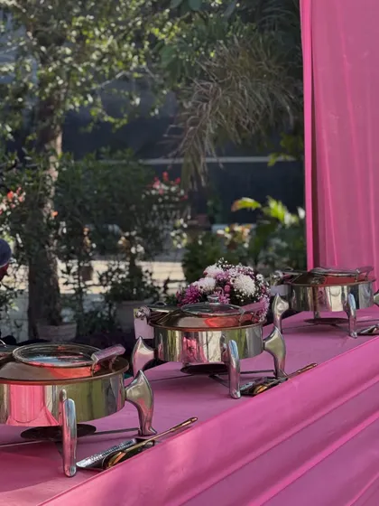 A vibrant pink-themed setup for a daytime wedding function. Our buffet counters can be customized to match your event's color palette and decor.