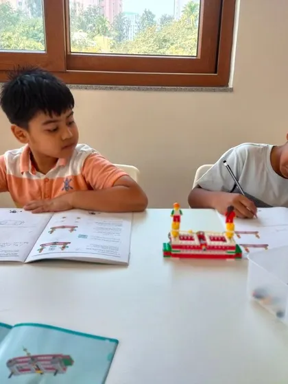 We balance hands-on building with structured learning. Here, students work on their designs in their workbooks before bringing them to life with LEGO bricks.