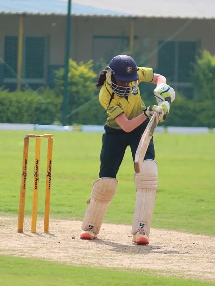 A young player demonstrates a solid defensive technique in front of the wickets.