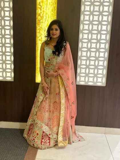 A client looking radiant in our mint green and peach designer lehenga. This shows how our rental outfits look for a real event, offering a high-end designer look for your special occasion.