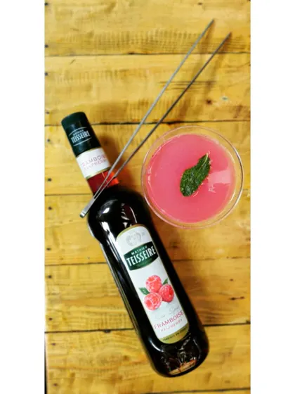 A Raspberry and Mint Daiquiri, pictured from above to show its vibrant color. This cocktail is a simple yet elegant mix of white rum, fresh lime, mint, and raspberry syrup, served chilled.