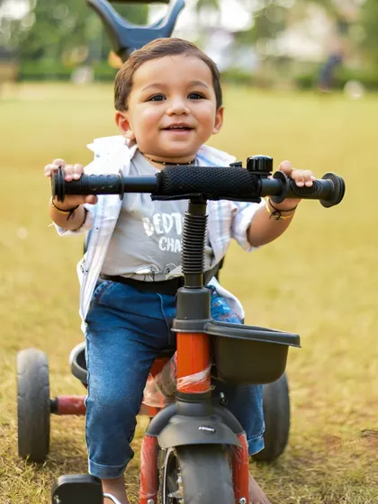 A close-up of a happy one-year-old on his tricycle. A perfect portrait for a first birthday shoot.