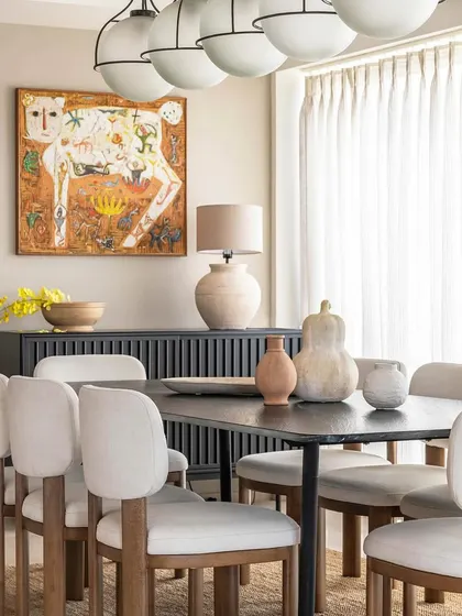 The dining room at Apartment 1600, where modern chairs and lighting are paired with traditional art.