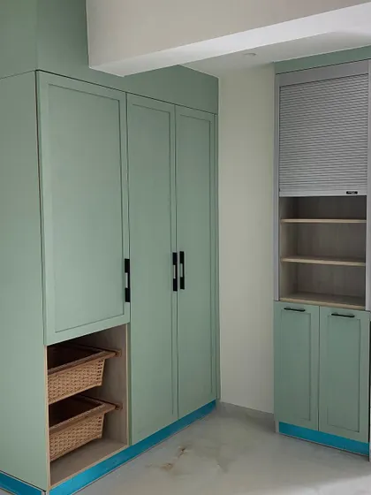 Additional storage in the pistachio kitchen, featuring a tall pantry unit with integrated wicker baskets for vegetable storage and a roller shutter for appliances.
