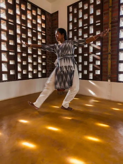 A dancer enjoying the play of light in a room with perforated brick walls. We design spaces that are not just functional but also inspire creativity and joy.