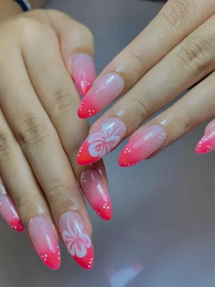 A tropical-inspired pink ombré on long stiletto nails, with hand-painted white hibiscus flowers.