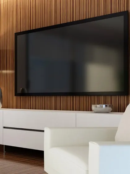 A perfect example of a modern media wall that blends seamlessly into the living room decor. The television is mounted on a rich, fluted wood panel, complemented by a minimalist white console that keeps the space feeling clean and uncluttered.