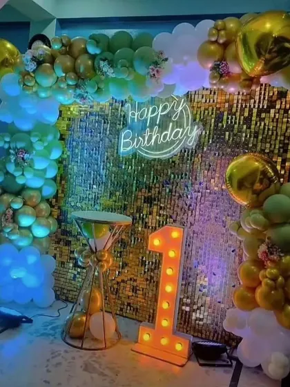 A first birthday party with a unique color scheme of green and gold against a sequin backdrop.