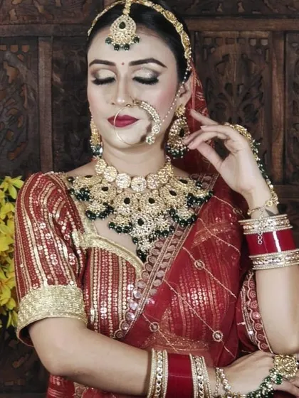A detailed shot of a bride wearing a heavy Kundan set with dark green beads. Notice the intricate work on the choker, nath, and maang tikka.