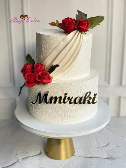 Celebrating a grand opening with elegance and sweetness. This two-tier cake features a beautiful white stencil design, fabric-like draping, and bold red roses.