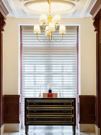 For the Godrej Experience Centre at The Imperial Hotel, we honored the building's heritage. This corridor showcases the original architectural details, like the ornate wood door frames, complemented by a classic console table and chandelier to enhance the historical context.