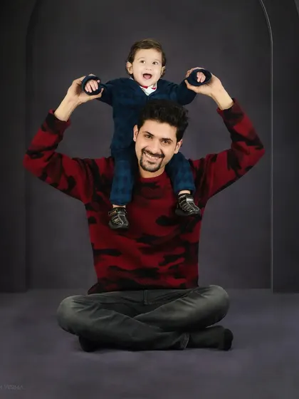 A father's joy is captured perfectly as his son sits on his shoulders, holding onto his dad's head. A classic pose that shows pure happiness.