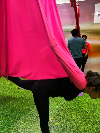 Explore your aerial journey with us. This student is using the hammock for a supported warrior pose, building strength and focus.