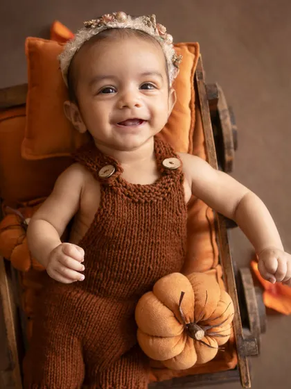 A big, gummy smile. This baby is having a wonderful time in her pumpkin-patch-themed setup.