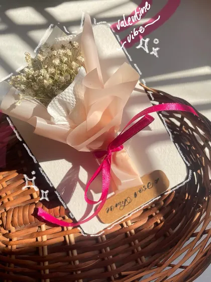 A close-up of the wrapping on the mini bouquet. The layers of paper and the pink ribbon make it feel like a tiny, precious gift.