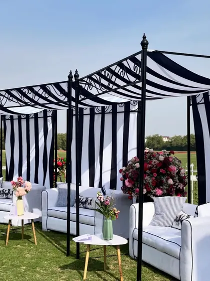 Chic black-and-white striped cabanas provided shaded seating for guests at the polo luncheon. The classic color scheme was accented with vibrant floral arrangements for a sophisticated look.