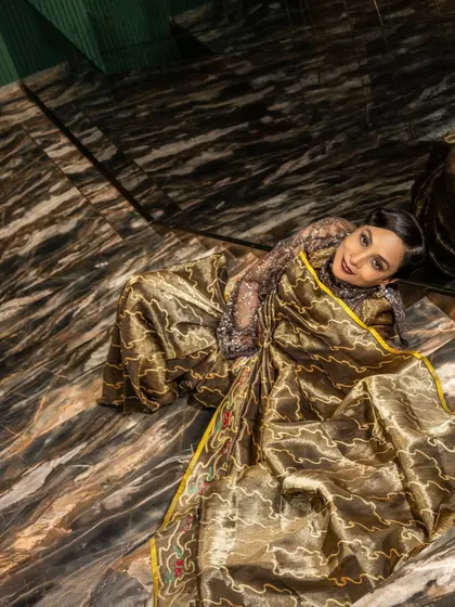 An artistic top-down shot showcasing the beautiful texture and fall of the handwoven silk saree.