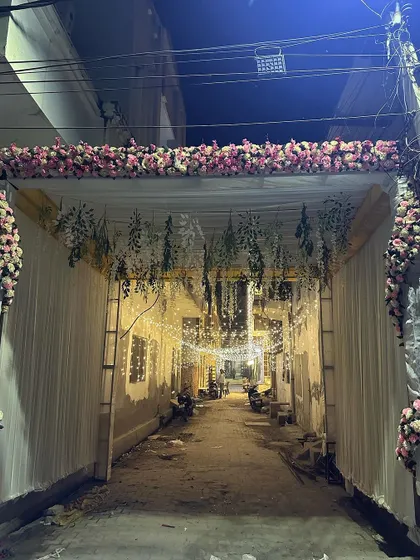 The entrance to a wedding celebration set up in a narrow street. The entire alley is transformed with drapes and hanging flowers, creating a magical pathway.