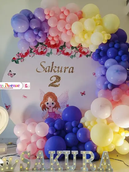 The front view of the Sakura fairy theme, showing the custom printed backdrop with the name and age, surrounded by a vibrant balloon garland.