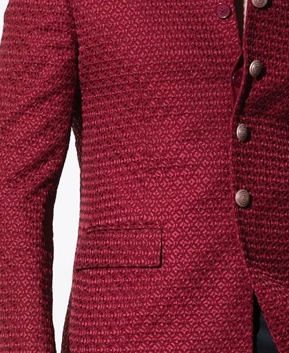 A detail shot of the crimson bandhgala's textured fabric. The intricate, geometric self-embroidery provides depth and a luxurious feel, showcasing our commitment to using premium materials.