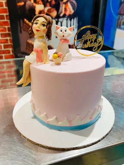 A sweet pink cake featuring a girl figurine and her cat, inspired by The Aristocats.