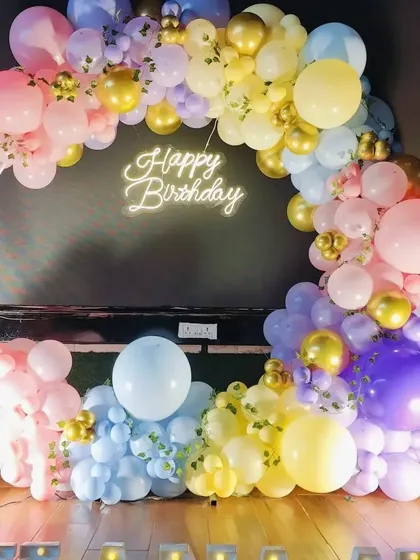 Another view of the pastel rainbow balloon ring, showing its placement against a dark wall which makes the colors stand out.