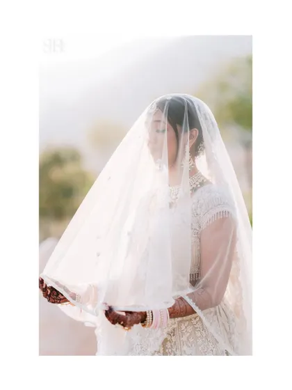An ethereal and dreamy bridal portrait. The bride is seen through her delicate veil, creating a soft, romantic, and almost painterly effect.