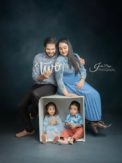The complete family together, with the parents looking lovingly at their children. The coordinated blue outfits create a harmonious and visually pleasing portrait.