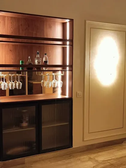 A sleek, built-in bar cabinet with wooden shelves, integrated lighting, and a mini-fridge. It's a perfect addition for those who love to entertain at home.