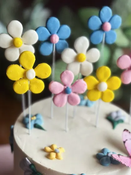 Blooming with sweetness. This floral cake is perfect for a third birthday, adorned with a garden of colorful, handcrafted sugar flowers and a delicate butterfly.