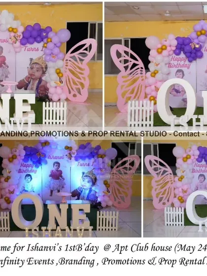 A whimsical butterfly theme for a first birthday at an apartment clubhouse. The setup includes a semi-arch backdrop with photos of the birthday girl, large butterfly wing props, and a "ONE" table, creating a personalized and magical celebration.