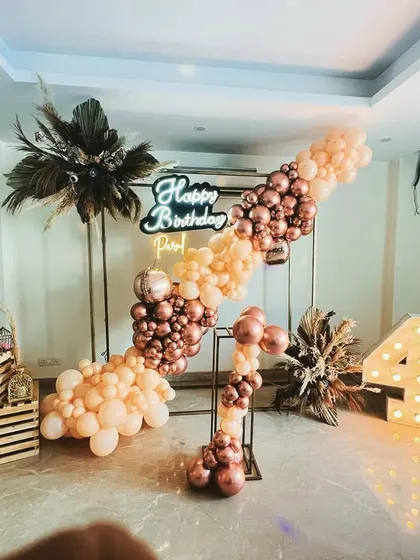 A full view of a chic boho-themed 40th birthday decoration, combining balloons, pampas grass, and marquee lights.