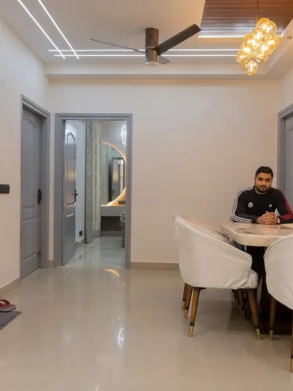 A simple yet elegant living and dining space. This image shows a clean layout with a dining table, a partition with built-in shelves, and a clear view into the other rooms, demonstrating effective space planning.