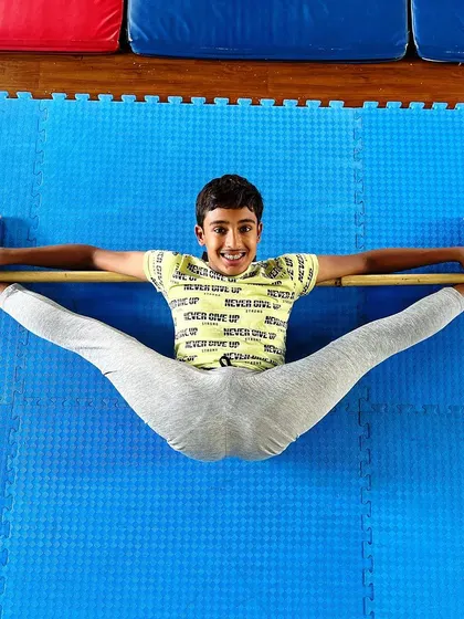 A smiling split. This young gymnast proves that working on flexibility can be fun and rewarding, proudly showing off his middle split.
