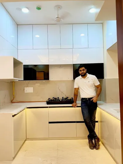 Here I am in a U-shaped modular kitchen finished in high-gloss white. This design maximizes counter space and storage, with cabinets reaching up to the ceiling for a clean, built-in look.