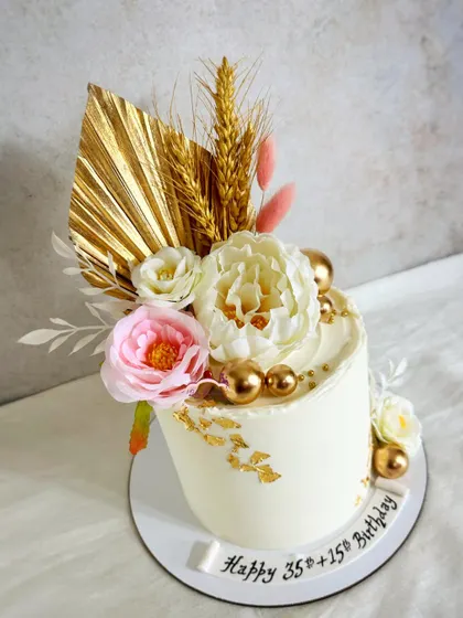 Pretty florals for a joint birthday celebration. This design features a mix of dried palms, gold spheres, and beautiful artificial flowers.