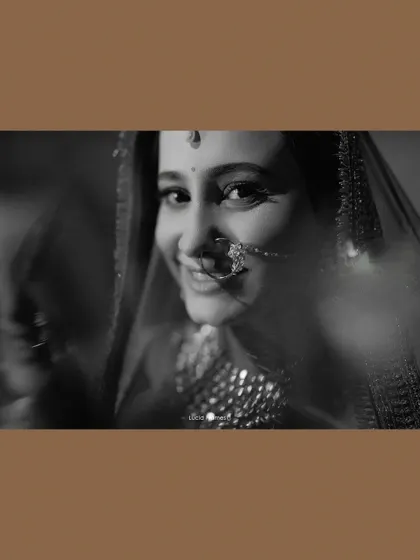 A soft, dreamy black and white portrait of the bride, her smile peeking through a veil.