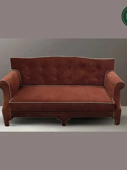 A full view of a classic sofa in rich terracotta fabric, showcasing its elegant silhouette and fine white piping. This piece is a testament to our ability to craft furniture with traditional, enduring appeal.